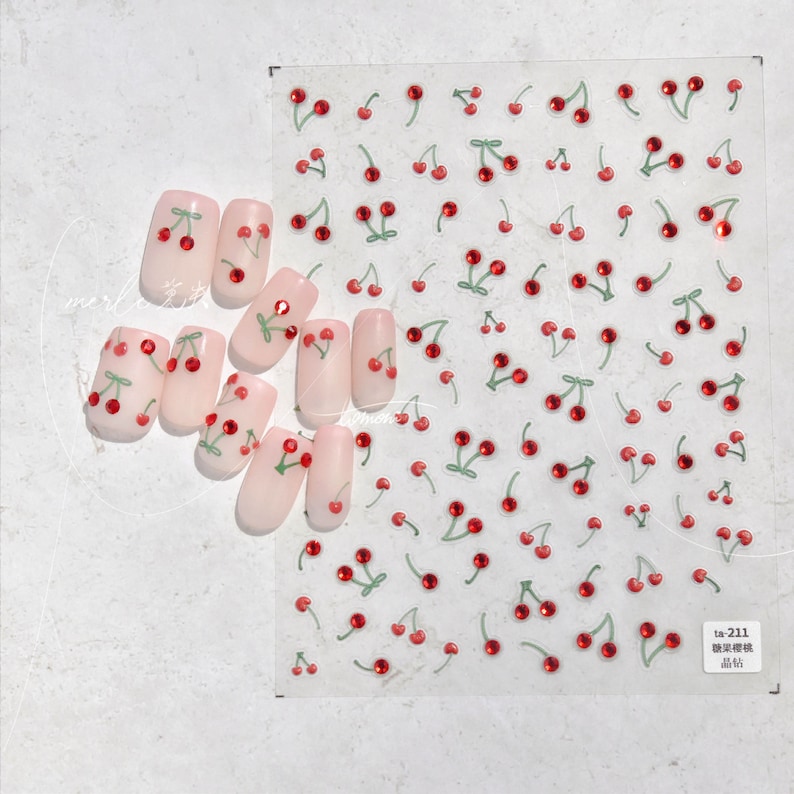 May include: A sheet of clear nail stickers with red and green cherry designs. The cherries have a single red rhinestone in the center. The sheet is labeled "ta-211  贴纸  贴纸".