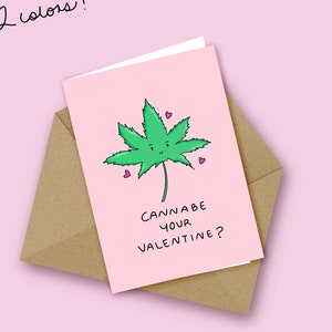 Könnte beinhalten: Rosa Valentinstagskarte mit einer grünen Cannabisblatt-Illustration mit lächelndem Gesicht und kleinen rosa Herzen. Die Karte mit dem Text "Cannabe your Valentine?" befindet sich in einem braunen Umschlag. Oben steht "2 Farben!"