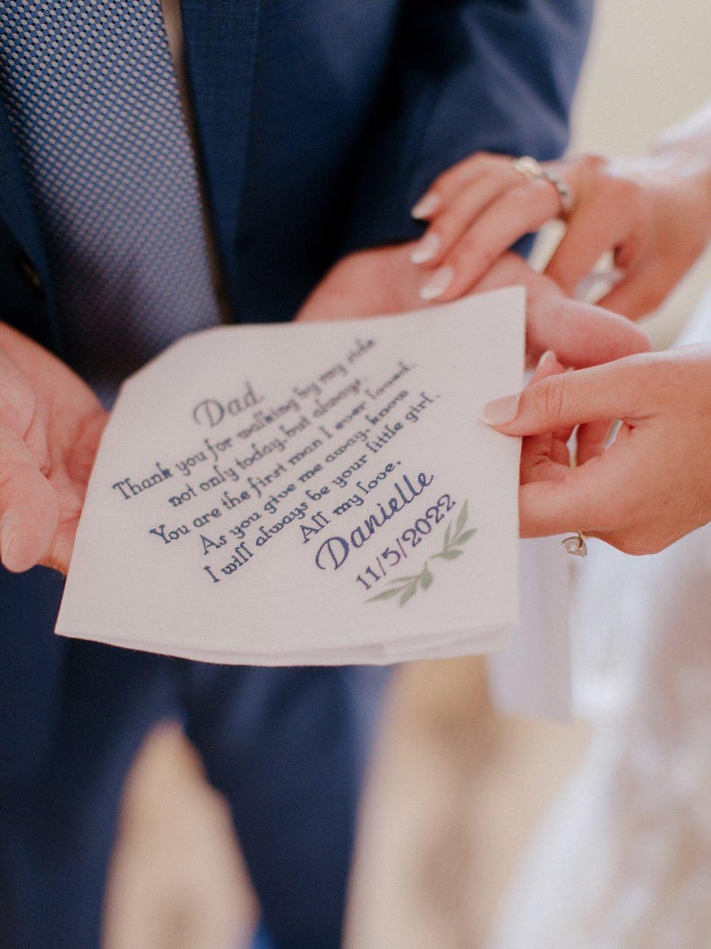 May include: A white handkerchief with blue text that reads "Dad Thank you for walking by my side not only today, but always. You are the first man I ever loved. As you give me away, know I will always be your little girl. Danielle 11/5/2022"