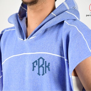 Könnte beinhalten: Ein blau-weiß gestreiftes Kapuzenhandtuch mit dem Monogramm "FRK" auf der Vorderseite.