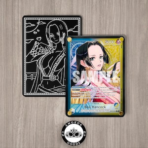 May include: Two trading cards featuring anime artwork. One card is black with a white outline of a woman. The other card is blue and yellow with a color illustration of a woman. The cards have text and are on a wooden surface.