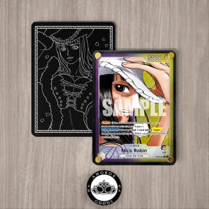 May include: A white ceramic mug with a black handle and the text "But First, Coffee" in a bold, black font. The mug is set against a blurred background, suggesting a cozy setting. The mug appears to be approximately 4 inches tall.