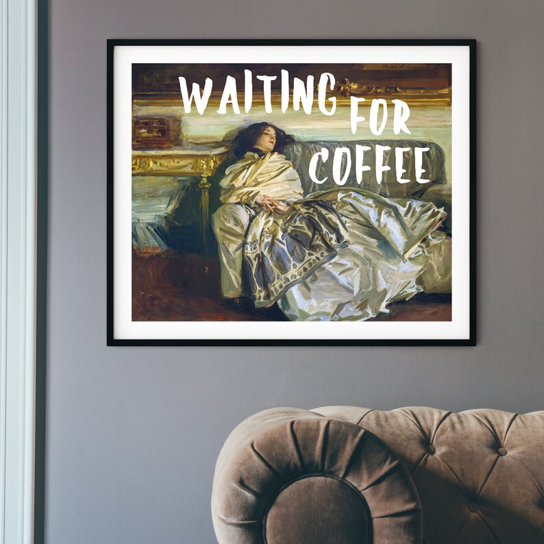 Op de afbeelding: Een ingelijste print van een schilderij van een vrouw die op een bank ligt. De tekst "WAITING FOR COFFEE" is in witte letters op een zwarte achtergrond geschreven.
