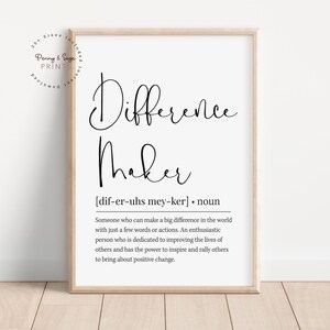 Può includere: Una stampa incorniciata con le parole "Difference Maker" in elegante scrittura nera. Sotto, è fornita la definizione di "Difference Maker". La stampa è in una cornice di legno chiaro, adatta per la decorazione.