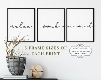 May include: Three black framed prints with white backgrounds and black calligraphy. The prints read "relax", "soak", and "unwind". The prints are hanging on a white wall with a wooden shelf and a decorative vase below. The text "5 FRAME SIZES OF EACH PRINT" is below the prints. A logo for Penny & Sage is below the text. The logo reads "PENNY & SAGE INSTANT DOWNLOAD PRINTABLES".