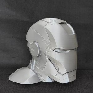 May include: A gray 3D printed model of a helmet with a faceplate and a neck piece. The helmet is designed to look like a futuristic or sci-fi helmet.