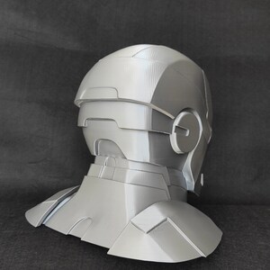 May include: A gray 3D printed helmet with a neck piece. The helmet has a textured surface and a design that resembles a futuristic robot.