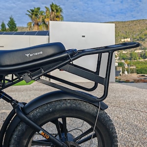 May include: Black electric bicycle with a rear rack and a black seat. The bike has a thick tire and a black fender. The brand name "Yanguie" is visible on the seat. The model is M20.