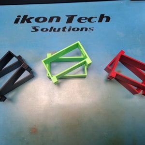 May include: Three 3D printed plastic stands in black, green, and red. The stands are stacked on top of each other. The stands are labeled "ikon Tech Solutions".