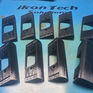 Puede incluir: Diez soportes de timbre de plástico negro impresos en 3D. Los soportes están diseñados para fijarse a una pared y tienen una ranura para insertar un timbre.