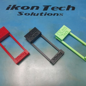 May include: Three 3D printed plastic holders for mining rigs. The holders are red, black, and green. Each holder has the text "ikon Tech" and "Mining" printed on it.