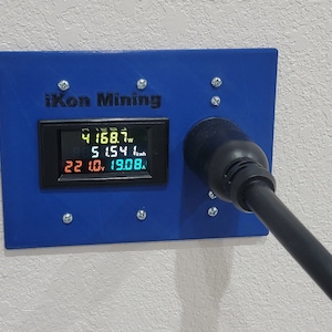 May include: A blue wall-mounted electrical outlet with a black power cord plugged in. A digital display shows the text "iKon Mining" and the readings "4168.7W", "5154.1kWh", "22.0V", and "1908.8A".