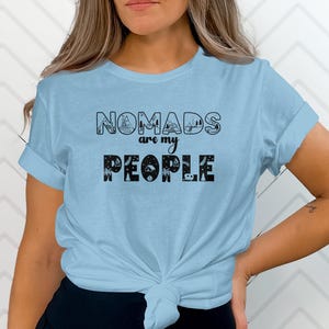 Light blue t-shirt with "NOMADS ARE MY PEOPLE" text and camping graphics.