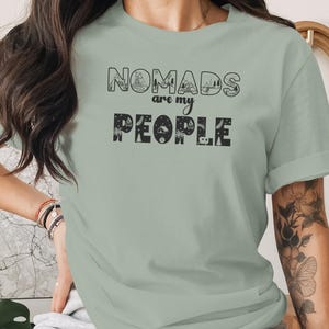 Green t-shirt with "Nomads are my People" text and travel icons.