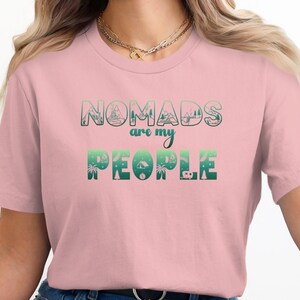 Pink t-shirt with "Nomads are my people" in a gradient green design.
