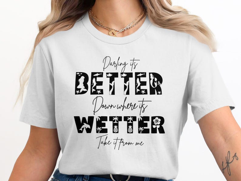 White t-shirt with black text "Darling it's BETTER Down Where it's WETTER" and beach graphics.