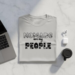 Gray t-shirt with "Nomads are my people" graphic, laptop, and coffee cup.