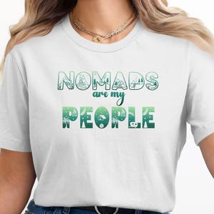White t-shirt with "Nomads are my people" text and green outdoor graphic.