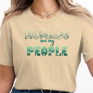 Cream t-shirt with "Nomads are my people" text and outdoor scene graphics.