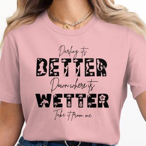 Pink t-shirt with "Darling its BETTER Down where its WETTER Take it from me" in black lettering.