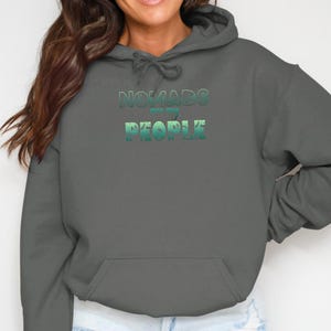 Dark gray hoodie with "Nomads are people" text in green and teal gradient.