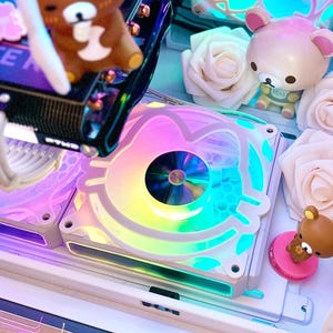 May include: A custom computer build with colorful LED fans and a clear side panel. The interior features brown bear figurines, white roses, and a graphics card with the word "FORCE" visible. The fans display a rainbow of colors.
