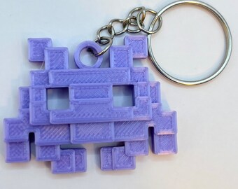 May include: A purple 3D printed keychain shaped like a pixelated space invader.