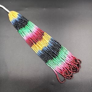 May include: A long strand of colorful gemstone beads, including red, pink, green, blue, and yellow. The beads are arranged in a repeating pattern, creating a vibrant and eye-catching display.