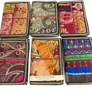 Peut inclure: Six carnets rectangulaires avec des couvertures en tissu présentant des motifs en patchwork de différentes couleurs, notamment or, rouge, violet, orange et bleu. Chaque carnet est attaché par un cordon et porte une étiquette HAND MADE PAPER NOTE BOOK.