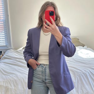 Puede incluir: Una chaqueta de color morado sobre una camiseta blanca y unos vaqueros azules claros.