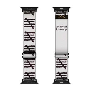May include: White Apple Watch band with a black and white pattern of diagonal lines. The band has the text "ZOX" and "count your blessings" printed on it.