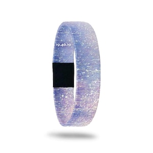 May include: A light blue and white patterned wristband with a black band. The wristband has the text "19.46.10" printed on it. The wristband is made of a soft, flexible material.