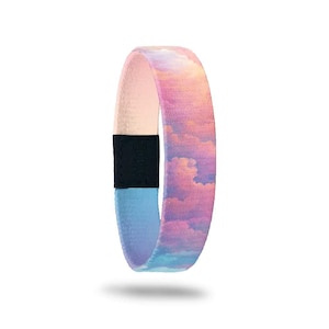 May include: A fabric wristband featuring a sky-themed design. The band transitions from light blue to pink, with a cloud pattern. A black section with text is visible. The wristband is a wearable accessory.