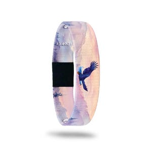 May include: A fabric wristband with a watercolor design. The band features a blue eagle in flight against a backdrop of purple and pink mountains. The text "23.40.31" is printed on the band. A black fabric section is in the middle.