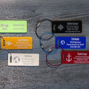 May include: Six colorful luggage tags with metal rings. Each tag has a different design and includes a name, address, and contact information. The designs include a palm tree, airplane, globe, compass, anchor, and world map.
