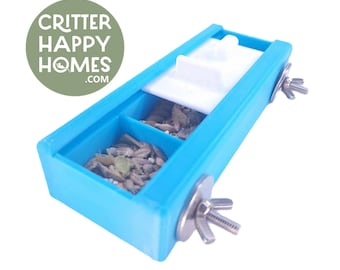May include: A blue plastic bird feeder with two compartments filled with birdseed. The feeder has a white plastic lid and two silver metal clamps for attaching it to a cage.
