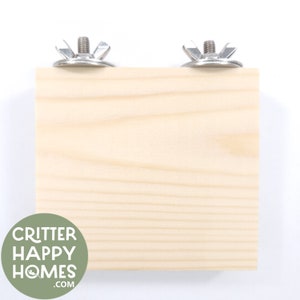 May include: A natural wood square platform with two metal mounting brackets. The platform is designed for small animals to climb and play on.
