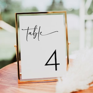 May include: A gold-framed table number sign with the text "Table 4" in black calligraphy.