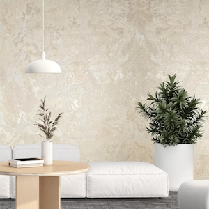 May include: A white couch with a white coffee table and a potted plant in a white pot. The wall behind the furniture is a light beige with a marbled pattern.