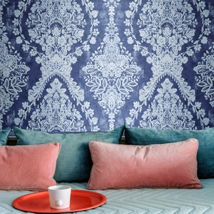 May include: A couch with a blue and white patterned wallpaper, teal and pink throw pillows, and a red tray with a white cup.