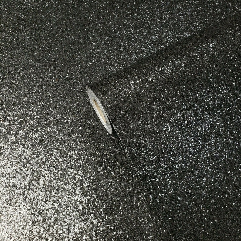 May include: A roll of black glitter wallpaper with a silver sparkle finish. The wallpaper is rolled up and the end of the roll is visible.