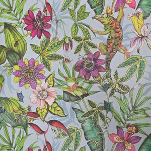 May include: A blue background with a tropical pattern featuring green leaves, pink, purple, and yellow flowers, green frogs, and a green and orange lizard.