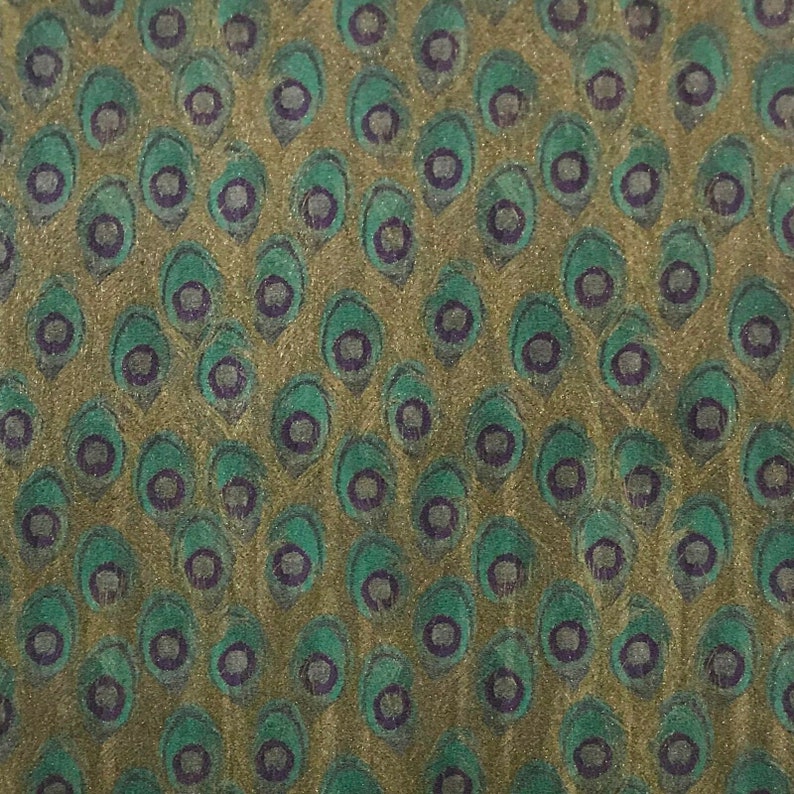 May include: A green and gold fabric with a repeating pattern of peacock feathers. The feathers are outlined in purple and have a textured appearance.