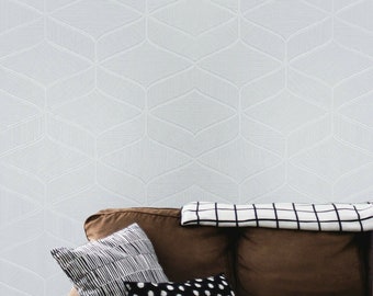 May include: A brown couch with a white and black checkered throw blanket and three pillows. The pillows are black and white striped, black with white polka dots, and black and white striped. The couch is in front of a white wall with a geometric pattern.
