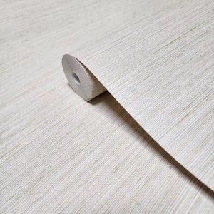 May include: A roll of natural beige wallpaper with a subtle woven texture. The wallpaper has a slightly rough, linen-like finish.