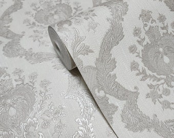 May include: A roll of off-white wallpaper with a repeating floral and scrollwork pattern in a muted silver-gray color. The wallpaper has a textured surface and a classic, elegant design, suitable for interior decoration.