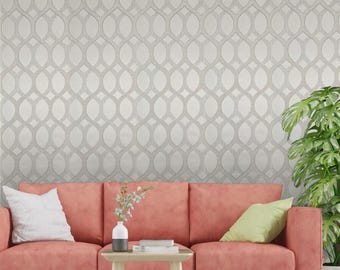 May include: A coral colored sofa with two pillows, one white and one green, sits in front of a wall with a white and gray geometric pattern wallpaper.