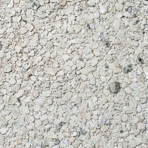 May include: Close-up of a white textured surface with small, irregularly shaped stones embedded in it. The surface has a rough, uneven texture.