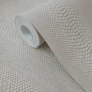 May include: A roll of light gray wallpaper with a textured snakeskin pattern. The wallpaper is partially unrolled, revealing the white backing. The design features a repeating scale-like texture, creating a realistic reptile skin effect.