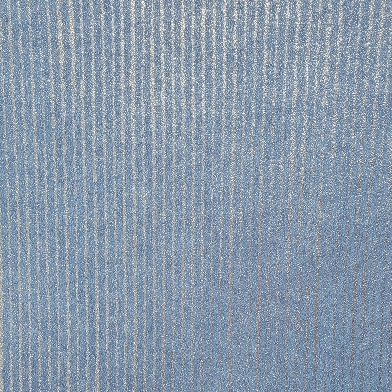 Puede incluir: Primer plano de una tela azul con un sutil patr&oacute;n de rayas plateadas. La tela tiene una textura casi peluda.